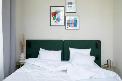 a bed with a green headboard and white pillows at Bob W Oosterpark in Amsterdam