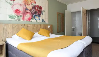 a bedroom with a large bed with yellow pillows at Boutique Hotel Asterisk, a family run hotel in Amsterdam