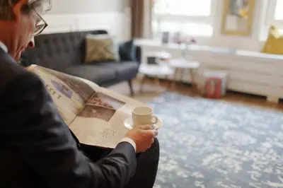 a man reading a newspaper while holding a cup of coffee at Boutique Hotel Asterisk, a family run hotel in Amsterdam