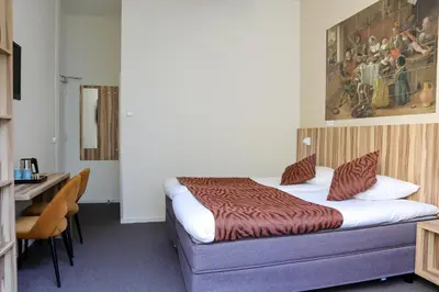 a hotel room with a bed and a desk and a painting at Boutique Hotel Asterisk, a family run hotel in Amsterdam