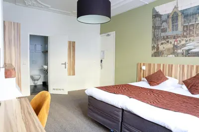 a hotel room with a bed and a chair in it at Boutique Hotel Asterisk, a family run hotel in Amsterdam