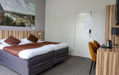 a bedroom with a bed and a table and a chair at Boutique Hotel Asterisk, a family run hotel in Amsterdam