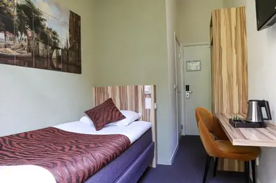 a hotel room with a bed and a table and a desk at Boutique Hotel Asterisk, a family run hotel in Amsterdam
