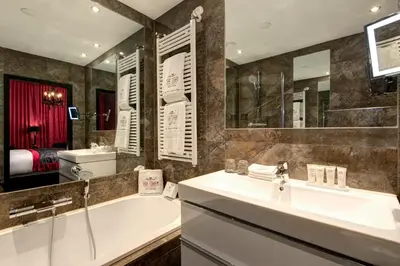 a bathroom with a tub and a sink and a mirror at The Toren Amsterdam, by The Pavilions in Amsterdam