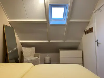 a room with a bed and a window and a chair at Casa Feliz in Egmond aan Zee