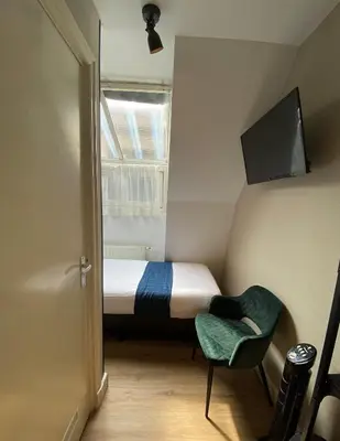 a small bedroom with a bed and a chair at Hotel Vondel Garden in Amsterdam