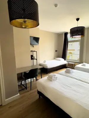 a hotel room with two beds and a desk at Hotel Vondel Garden in Amsterdam