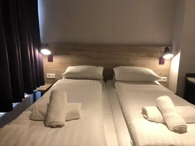 a bedroom with two beds with white sheets and towels at Facade Hotel Amsterdam in Amsterdam