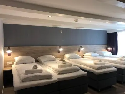 a room with three beds with white pillows on them at Facade Hotel Amsterdam in Amsterdam