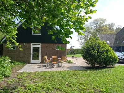 a patio with chairs and a table in front of a house at Uniek vakantiehuis - nabij molen, meer, strand & stad' in Hoorn