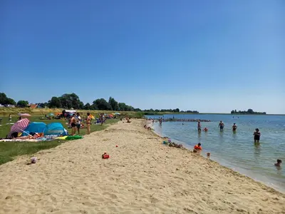 a group of people on a beach near the water at Uniek vakantiehuis - nabij molen, meer, strand & stad' in Hoorn