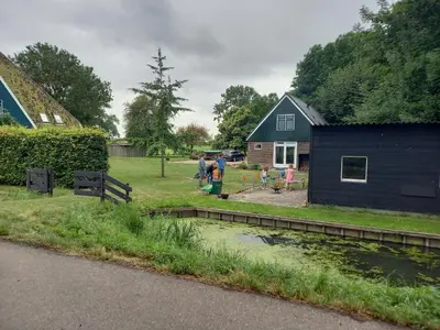 a group of people standing in a yard next to a house at Uniek vakantiehuis - nabij molen, meer, strand & stad' in Hoorn