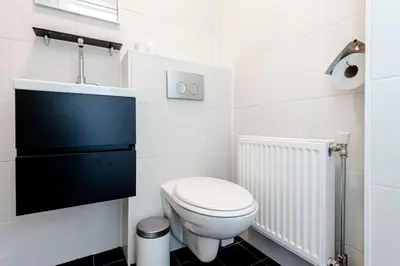 a white bathroom with a toilet and a sink at Sea Shell apartment in Zandvoort
