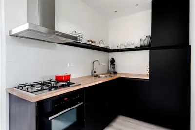 a kitchen with black cabinets and a stove top oven at Sea Shell apartment in Zandvoort