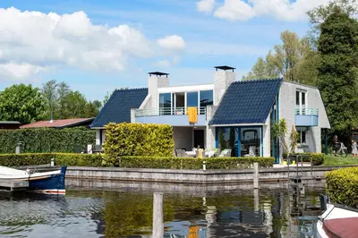 a house on the water with a boat in it at Amsterdam / Loosdrecht Rien van den Broeke Village in Loosdrecht