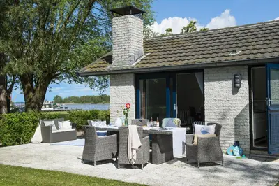 a patio with a table and chairs and a building at Amsterdam / Loosdrecht Rien van den Broeke Village in Loosdrecht