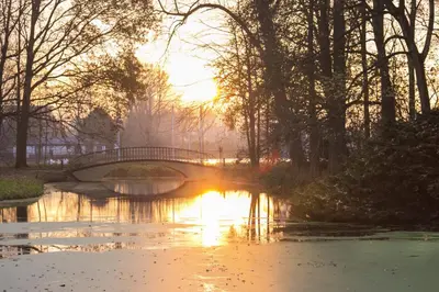 a bridge over a river with the sun setting at Landgoed Oud Poelgeest - Leiden in Oegstgeest