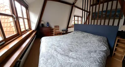 a bedroom with a bed in a room with windows at Onder de Boomen in Bergen