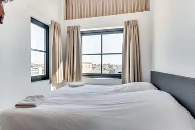 a bedroom with a white bed and two windows at Vernieuwd Zeezicht Villa Zee Luxe in Bergen aan Zee