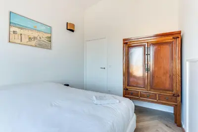 a bedroom with a wooden cabinet next to a bed at Vernieuwd Zeezicht Villa Zee Luxe in Bergen aan Zee