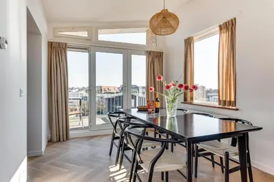 a dining room with a table and chairs and windows at Vernieuwd Zeezicht Villa Zee Luxe in Bergen aan Zee