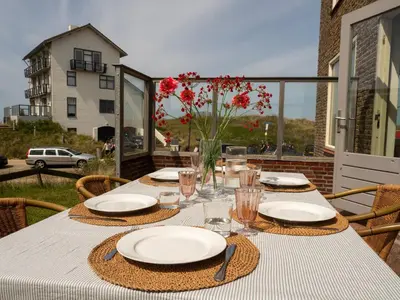 a table with plates and glasses on a patio at Vernieuwd Zeezicht Villa Zee Luxe in Bergen aan Zee