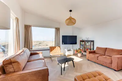 a living room with two couches and a tv at Vernieuwd Zeezicht Villa Zee Luxe in Bergen aan Zee