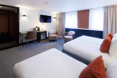 a hotel room with two beds and a desk at Huygens Place Amsterdam in Amsterdam