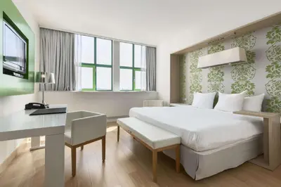 a bedroom with a large white bed and a desk at NH Amsterdam Noord in Amsterdam