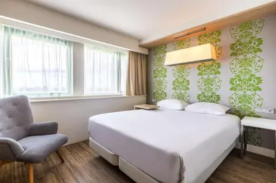 a bedroom with a white bed and a chair at NH Amsterdam Noord in Amsterdam