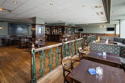 a restaurant with wooden tables and chairs and a balcony at NH Amsterdam Noord in Amsterdam