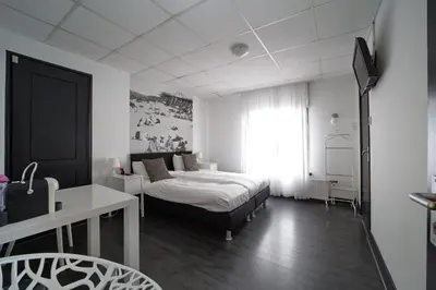 a bedroom with a bed and a desk and a window at Hotel Zeespiegel in Zandvoort