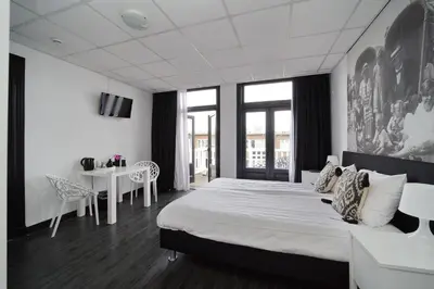 a bedroom with a large bed and a table at Hotel Zeespiegel in Zandvoort