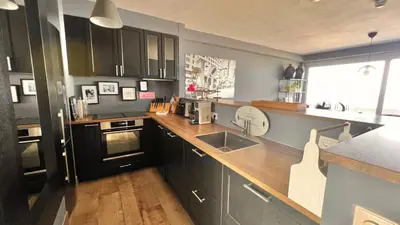 a kitchen with black cabinets and a wooden counter top at Ocean BreezeApartment: WakeUp 2 Sound of the Waves in Zandvoort