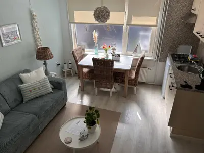 a living room with a couch and a table and a kitchen at Have a nice stay! - Voilà! - beach at 500m- free parking in Noordwijk aan Zee
