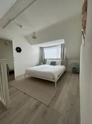 a white bedroom with a bed and a window at Have a nice stay! - Voilà! - beach at 500m- free parking in Noordwijk aan Zee