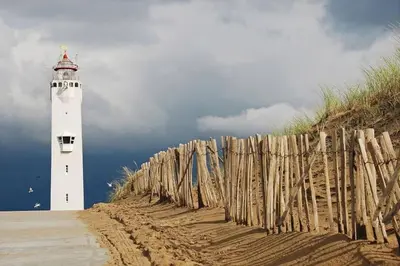 a lighthouse on the beach next to a fence at Have a nice stay! - Voilà! - beach at 500m- free parking in Noordwijk aan Zee