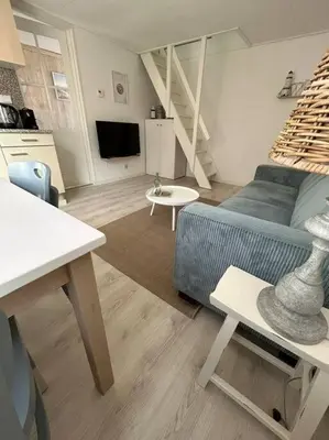 a living room with a blue couch and a kitchen at Have a nice stay! - Voilà! - beach at 500m- free parking in Noordwijk aan Zee