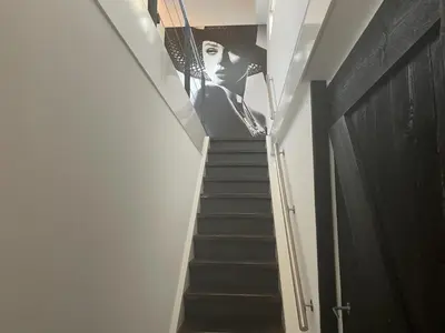 a staircase with a poster of a woman on the wall at Kapberg 'Om de Noord' in Warmenhuizen