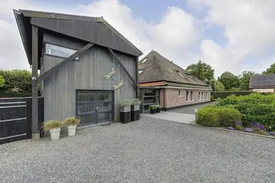 a barn style house with a garage at Kapberg 'Om de Noord' in Warmenhuizen