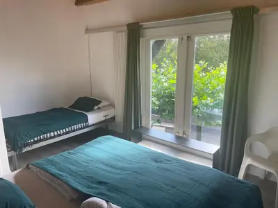 a bedroom with two beds and a large window at Kapberg 'Om de Noord' in Warmenhuizen