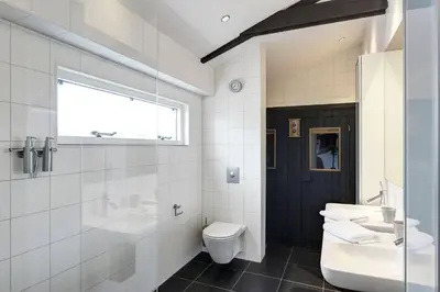 a white bathroom with a sink and a toilet at Kapberg 'Om de Noord' in Warmenhuizen