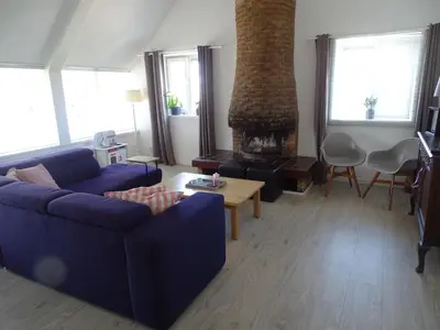a living room with a blue couch and a fireplace at Guesthouse Wormer in Wormer