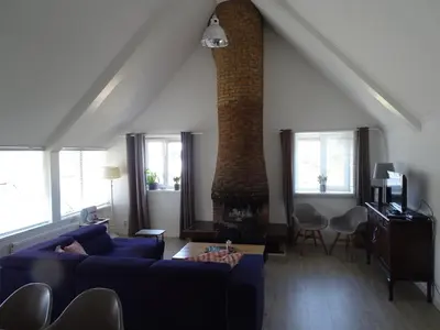 a living room with a blue couch and a brick fireplace at Guesthouse Wormer in Wormer