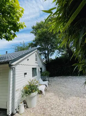 a white shed with two white benches next to it at Duinstudio Bergen in Bergen