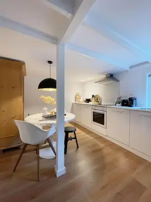 a kitchen with a white table and a white chair at Duinstudio Bergen in Bergen