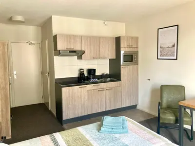 a kitchen with wooden cabinets and a table in a room at Nicolette Apartments in Katwijk