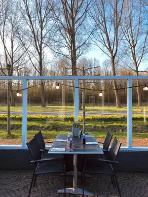 a table and chairs on a patio with a view of a park at Hotel Molengroet in Noord-Scharwoude