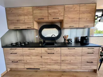 a kitchen with wooden cabinets and a black counter top at NEW - Little Asia - Stunning Boathouse on a lake Near Amsterdam with Sauna in Vinkeveen