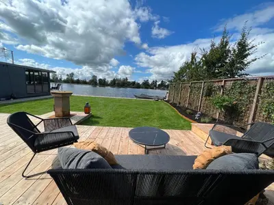 a patio with a couch and chairs on a wooden deck at NEW - Little Asia - Stunning Boathouse on a lake Near Amsterdam with Sauna in Vinkeveen